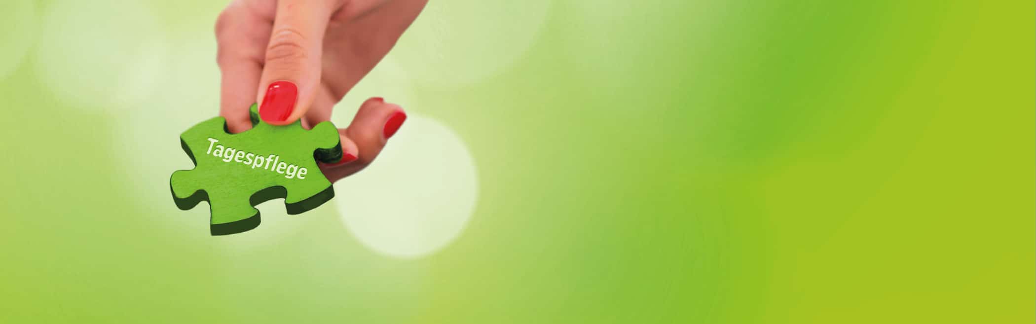 Hand hält ein grünes Puzzleteil mit der Aufschrift ‚Tagespflege‘.