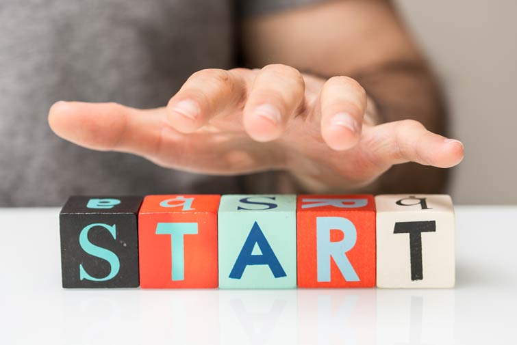 Existenzgruender_755x505px Hand schwebt über bunten Holzklötzen, die das Wort „START“ bilden.