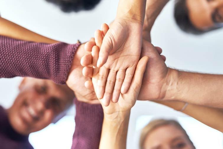 Interessengemeinschaften Mehrere Personen legen Ihre Hände übereinander.