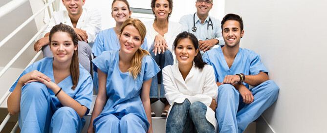 Medizinisches Personal sitzt auf einer Treppe und macht ein Gruppenfoto.